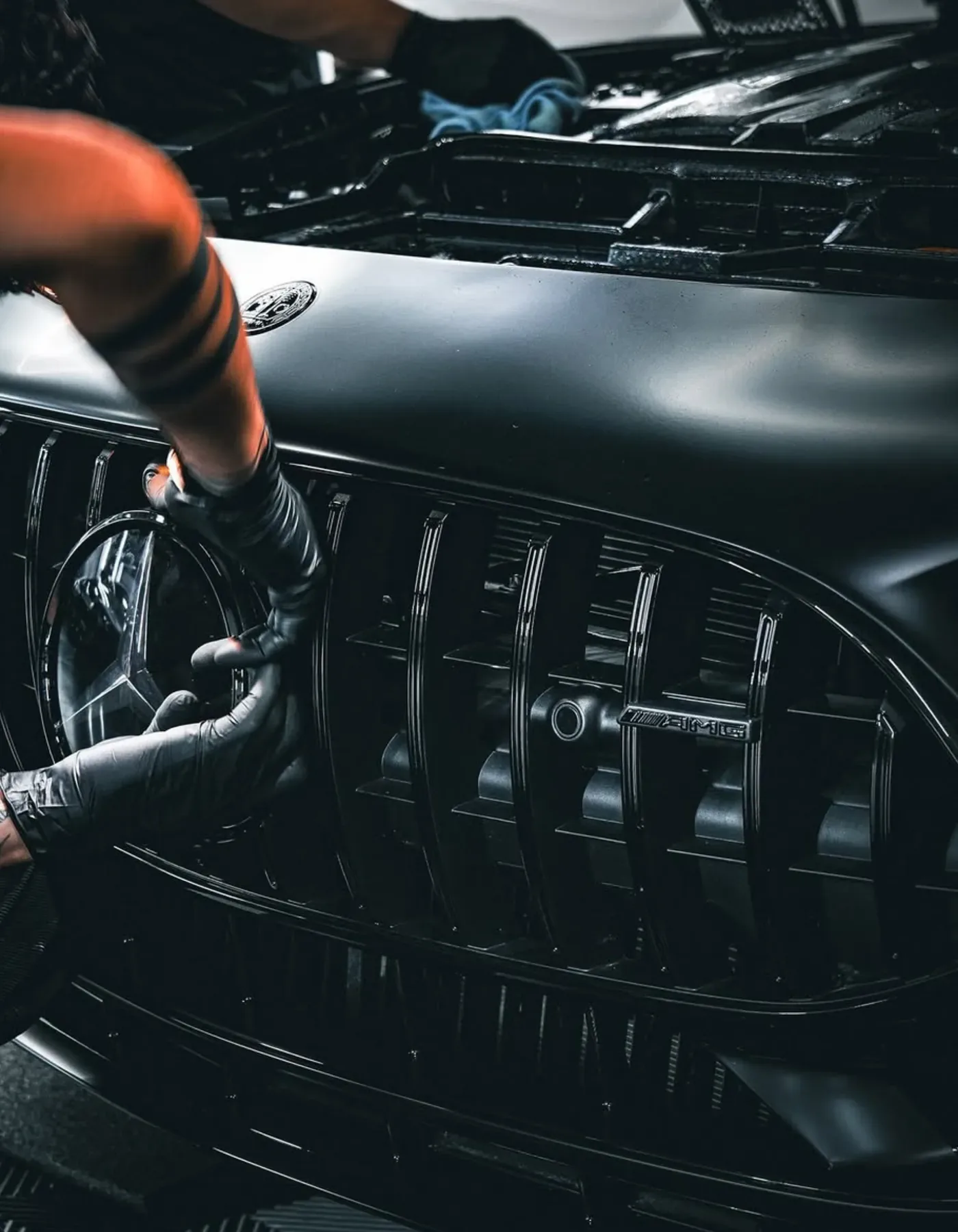 Gloved hands detailing a gloss black grille